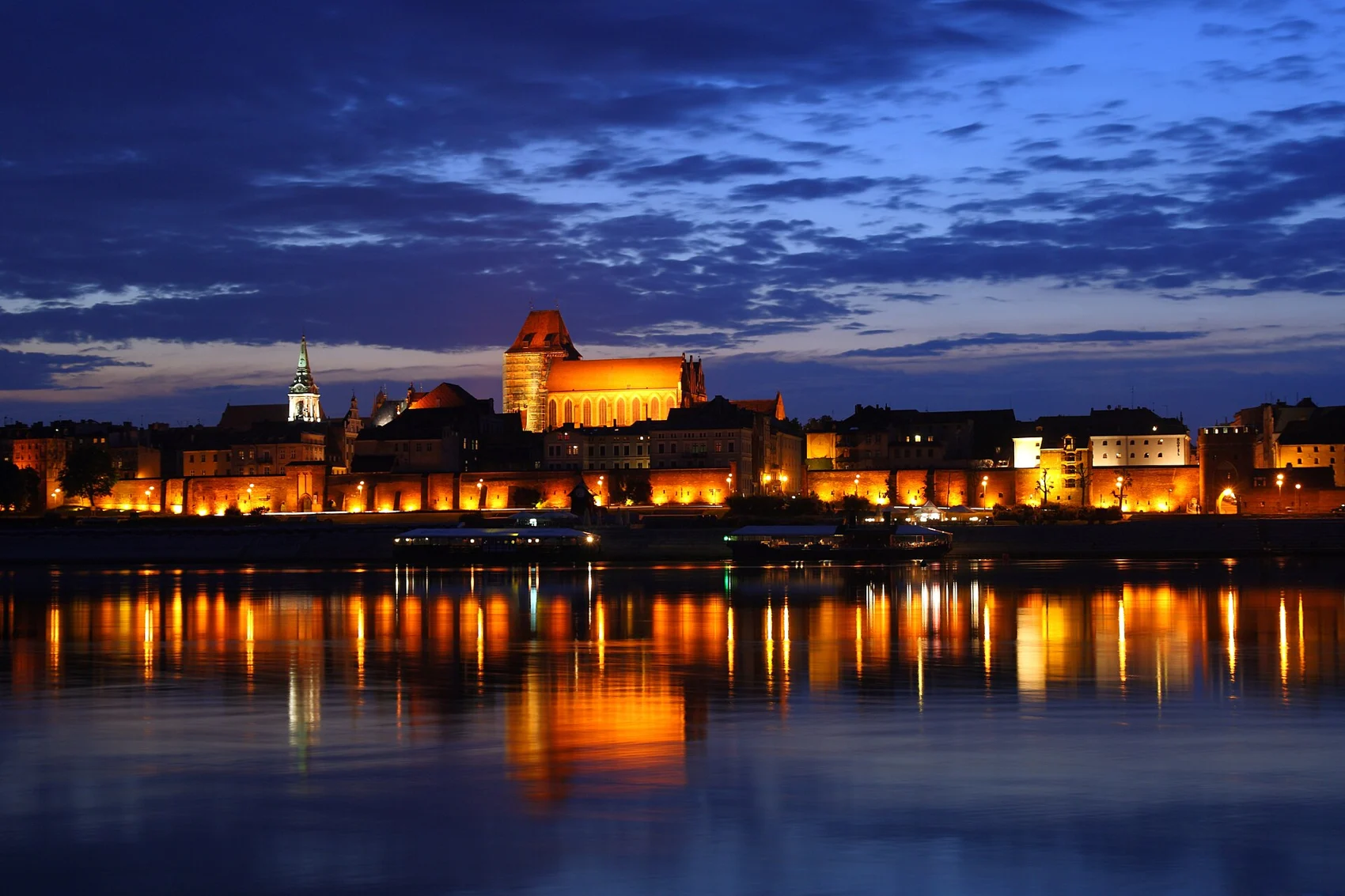 Torun waterfront illuminated at night; city context photograph